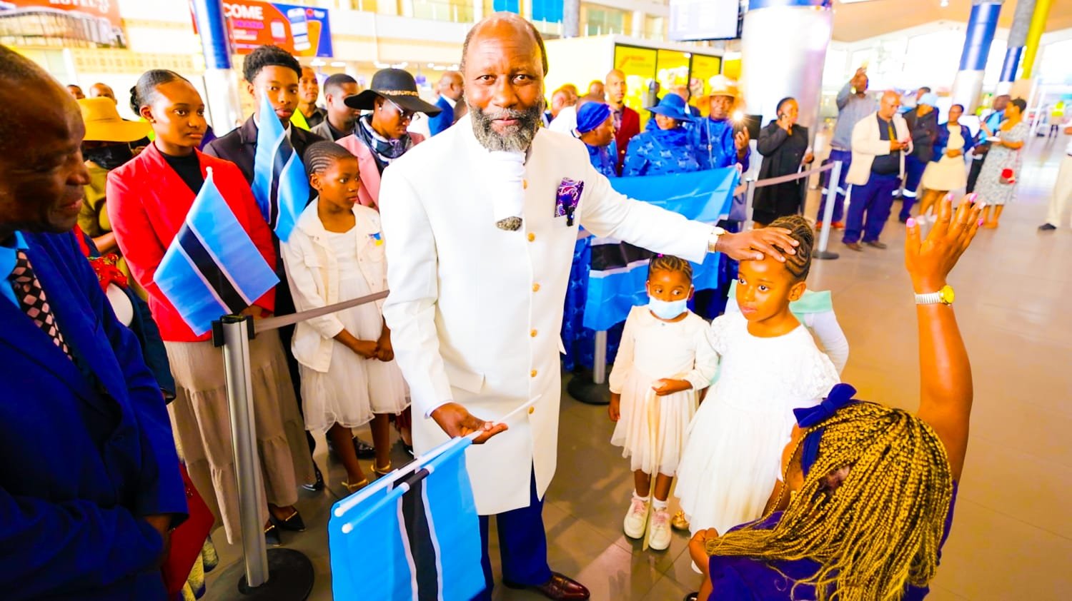 Prophet Dr. David Edward Owuor blesses a child amid well-wishers waving the Botswana flag